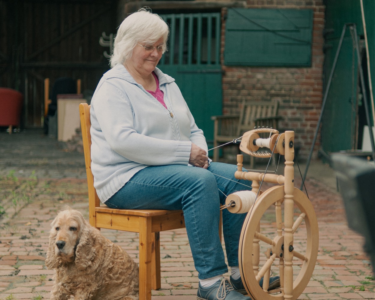 Cornelia am Spinnrad mit ihrem Hund Thomas